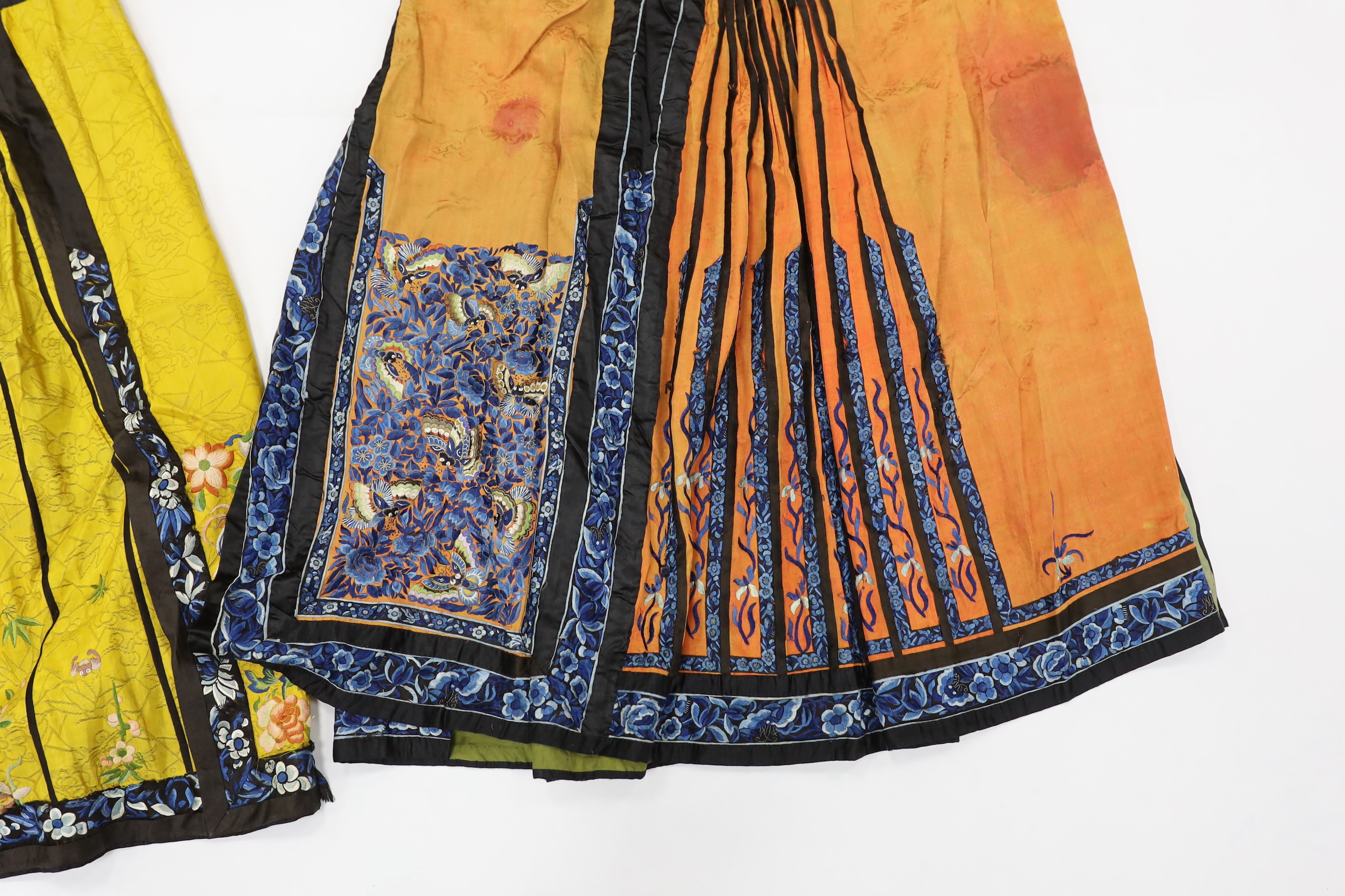 A late Chinese Qing yellow silk damask wedding skirt, with polychrome coloured silk embroidery, together with a similar coral silk damask blue embroidered wedding skirt